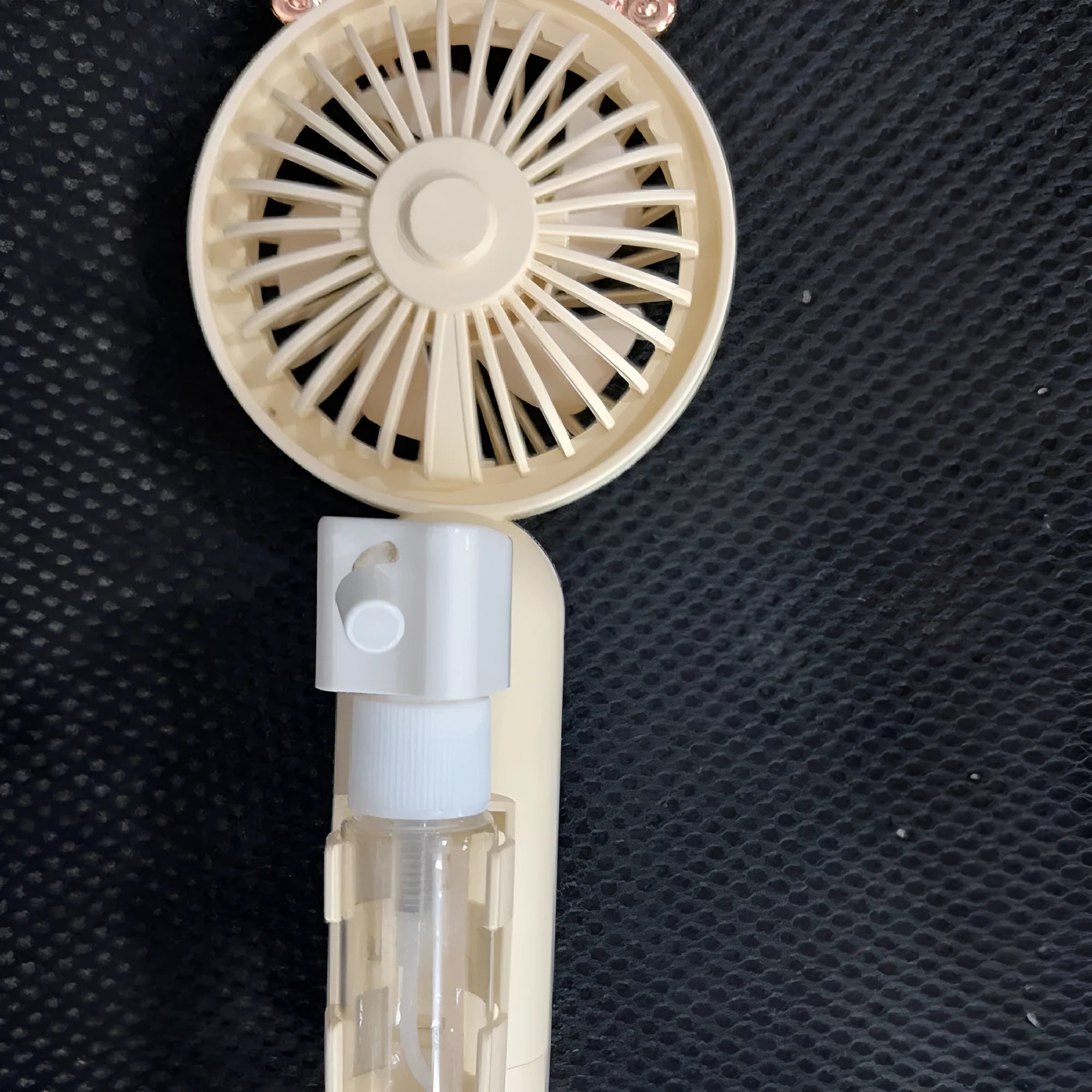 Compact plastic USB-powered desk fan with nozzle, shown in apricot colour on a wooden desk.