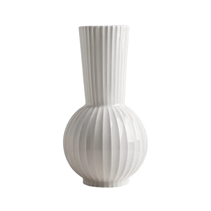 White ceramic ball vase with vertical stripes on a wooden table, with optional artificial purple orchid stems.