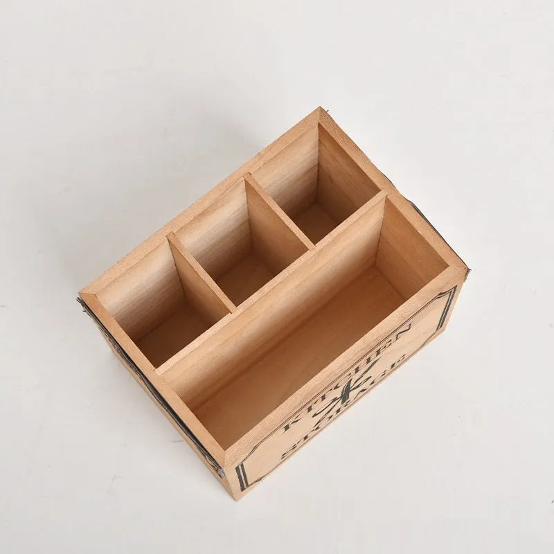 Open-top wooden kitchen storage box with internal grid divider for organising utensils.