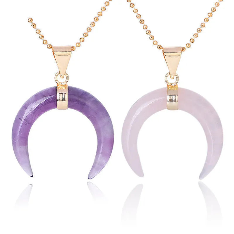A moon-shaped pendant necklace with a pink natural stone on a copper-coloured chain against a white background.