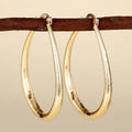 Close-up of women's geometric drop-shaped clip-on earrings with ring and line design in a copper and electroplated finish.