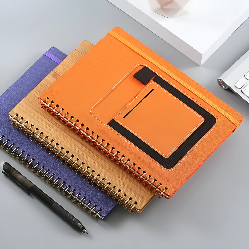 Erasable coil-bound notebook with stone paper, shown with pen and cloth on a wooden desk.