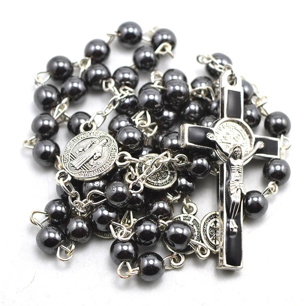 Black rosary necklace with hematite beads and zinc alloy cross on plain background