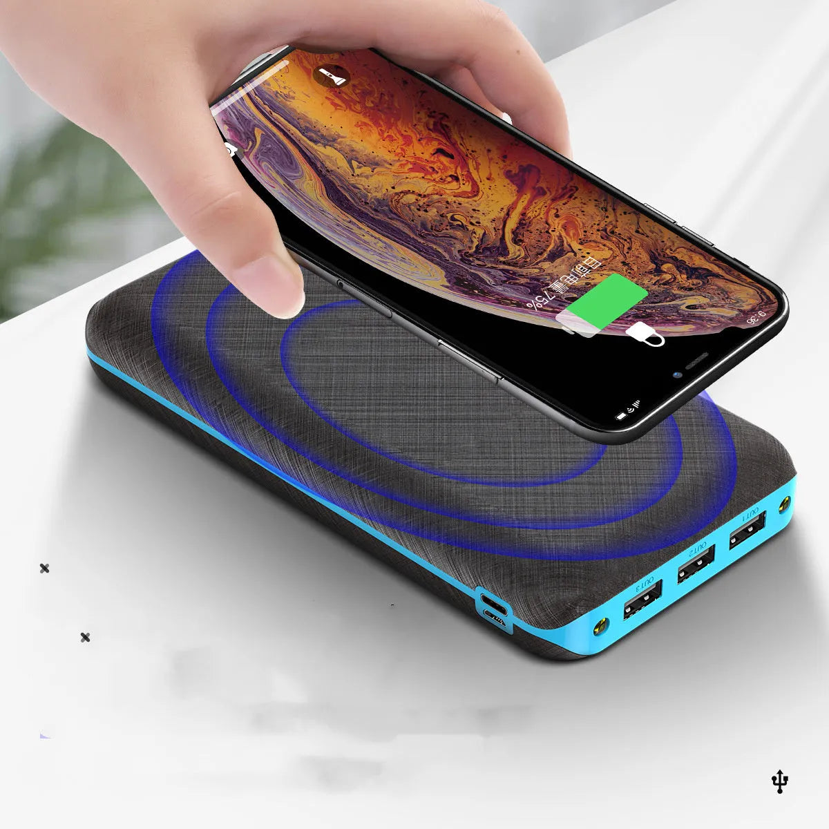 Black portable power bank with Qi wireless charging pad, three USB ports, and an LED flashlight on the front.