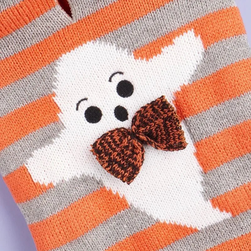 Orange knitted dog sweater with striped pattern, fur ball trim, and a hood for Halloween.