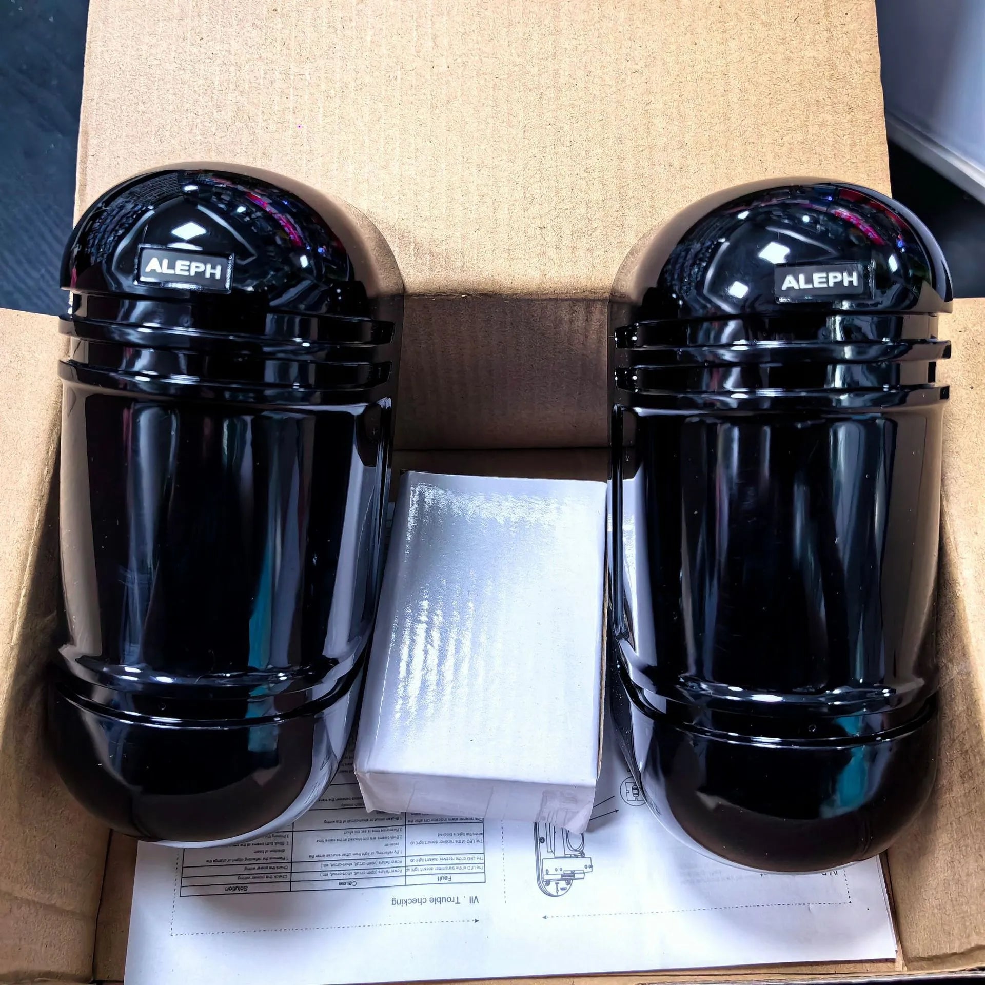 A pair of black infrared beam detectors for long-range perimeter security alarm systems.