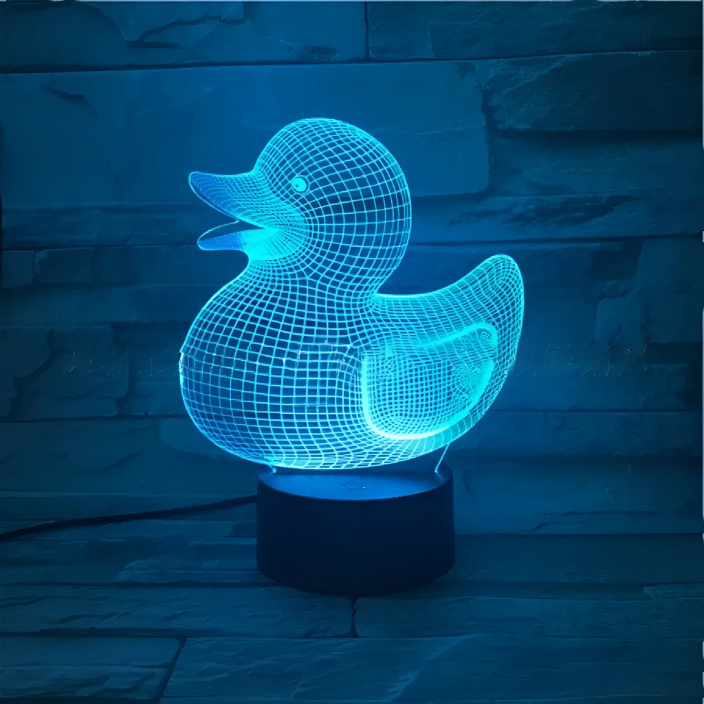 Yellow 3D duck-shaped LED night light on a table with remote control, showing multi-colour glow.