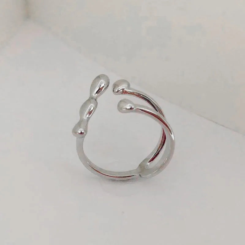 Gold and silver coloured brass opening ring with spherical design on a white background.