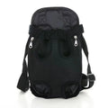 A person wearing a black nylon dog carrier backpack on their chest, with a small dog inside looking out.