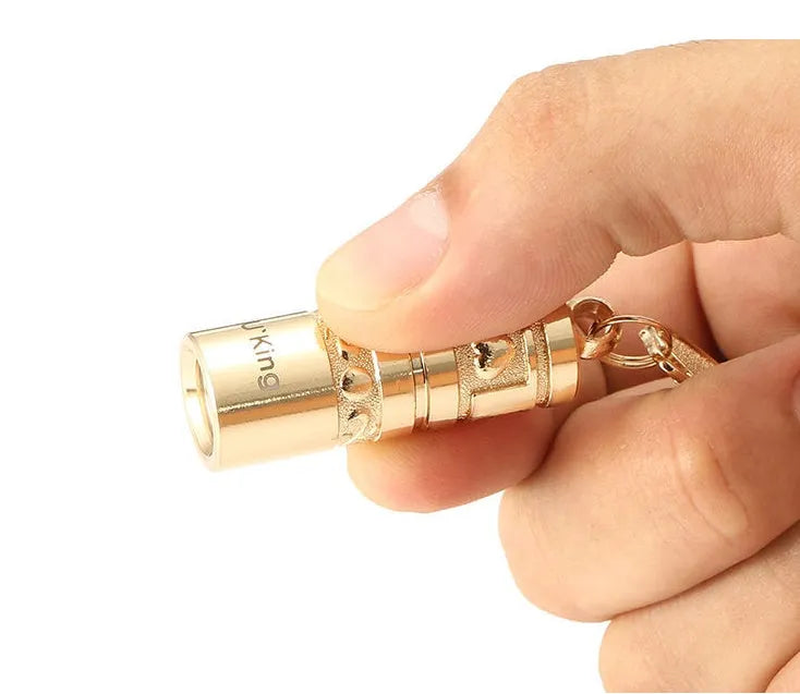 Gold-coloured waterproof mini LED keychain flashlight with zinc alloy housing on a key ring.