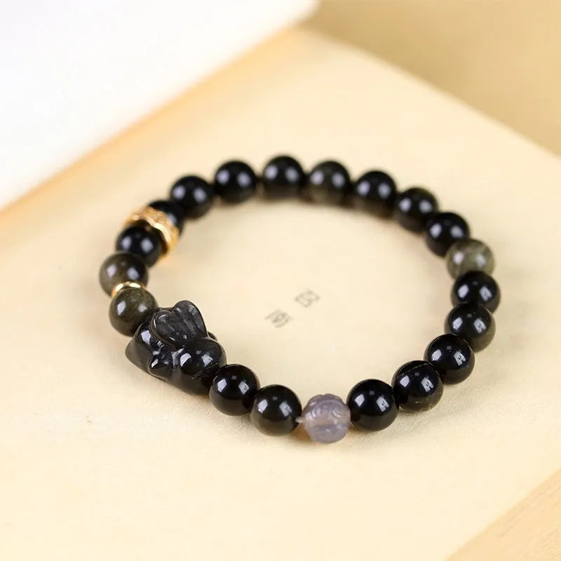 Handmade Chinese style bracelet with lying rabbit charm, grey agate bead, and brass on a black background.