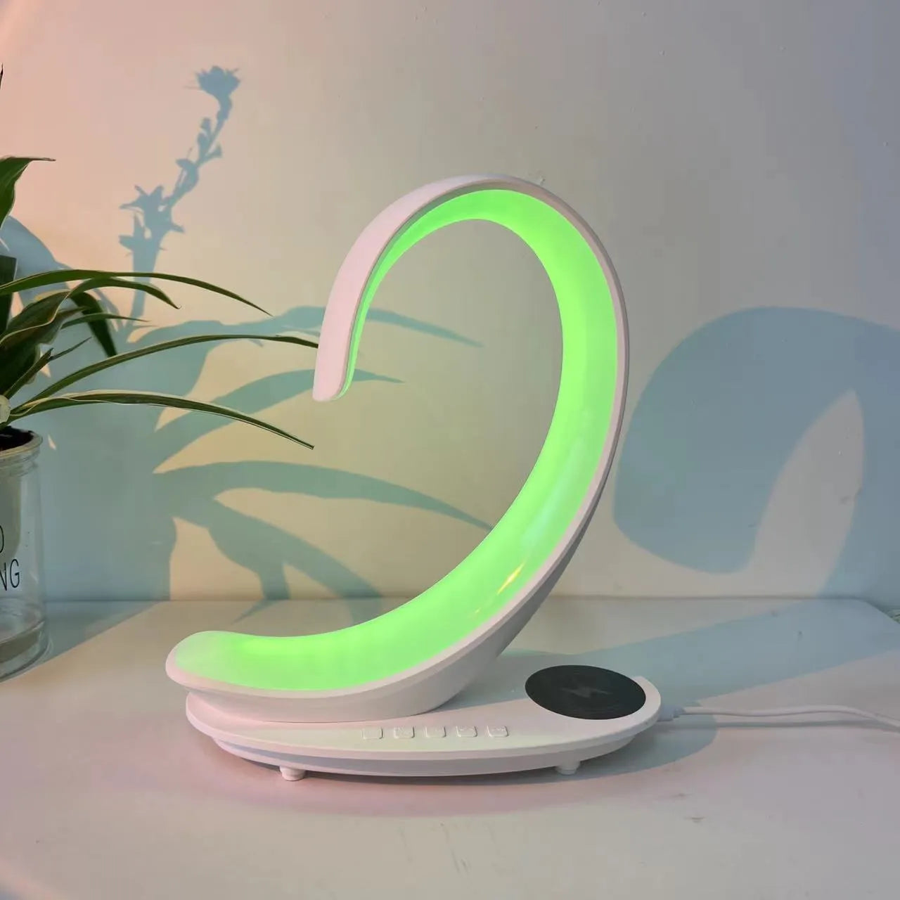 White swan-shaped desk lamp with wireless charging base and Bluetooth speaker emitting colourful light.