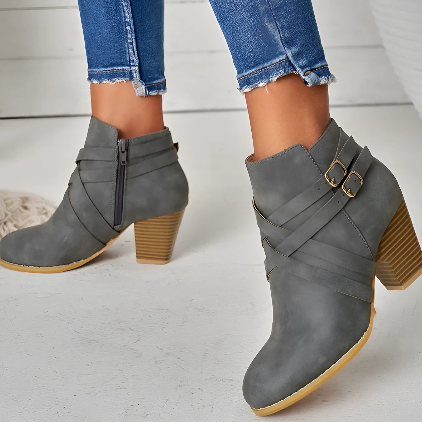 Grey PU leather short ankle boot with a 7cm chunky heel, side zip, and belt buckle on a wooden background.