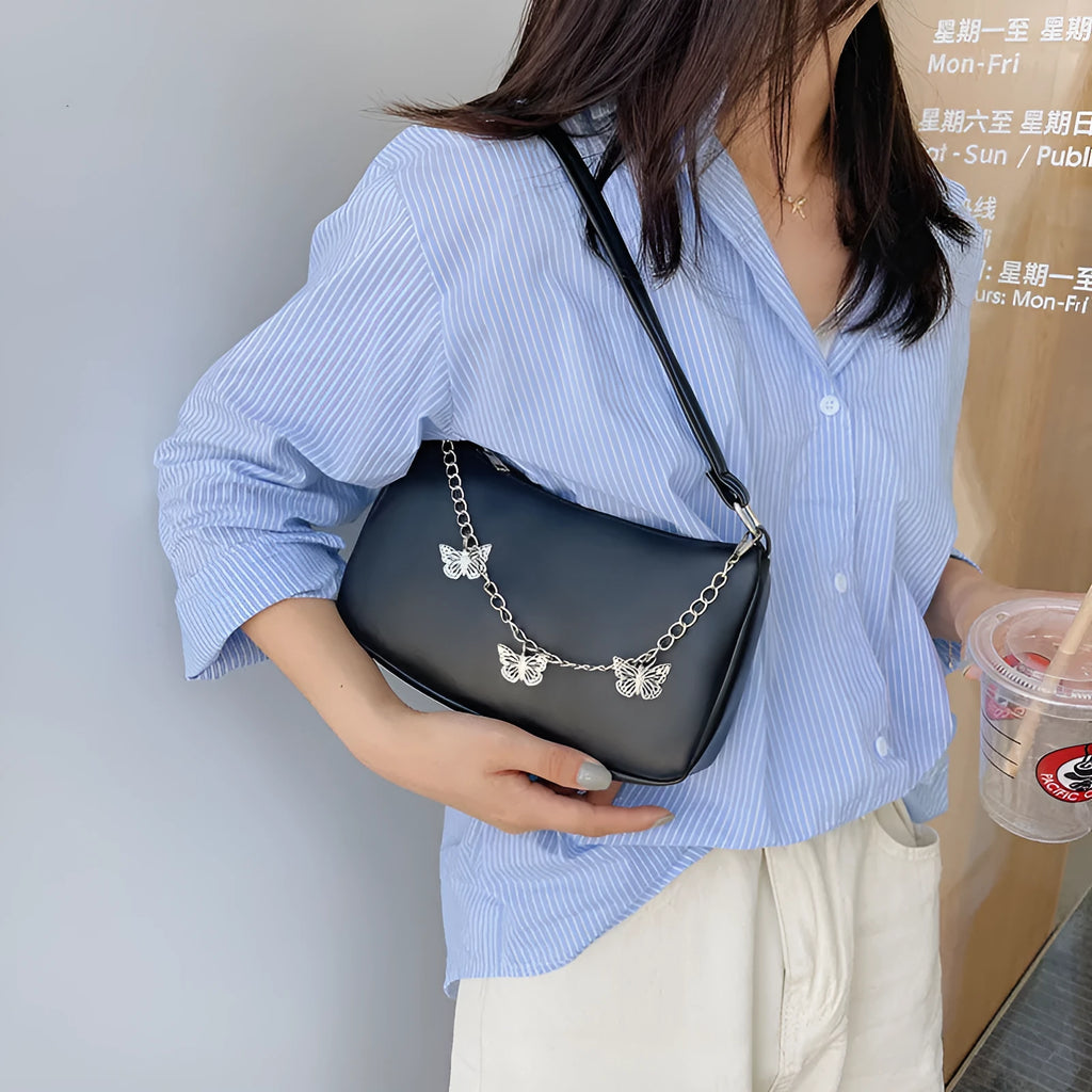 Women's butterfly chain underarm bag in black colour showing crossbody strap and three-dimensional pocket
