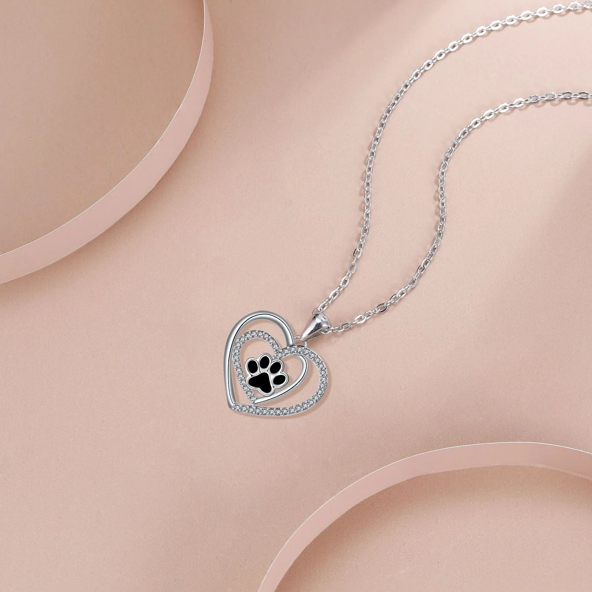 Close-up of a heart-shaped copper necklace pendant featuring a detailed dog's paw print design on a cross chain.