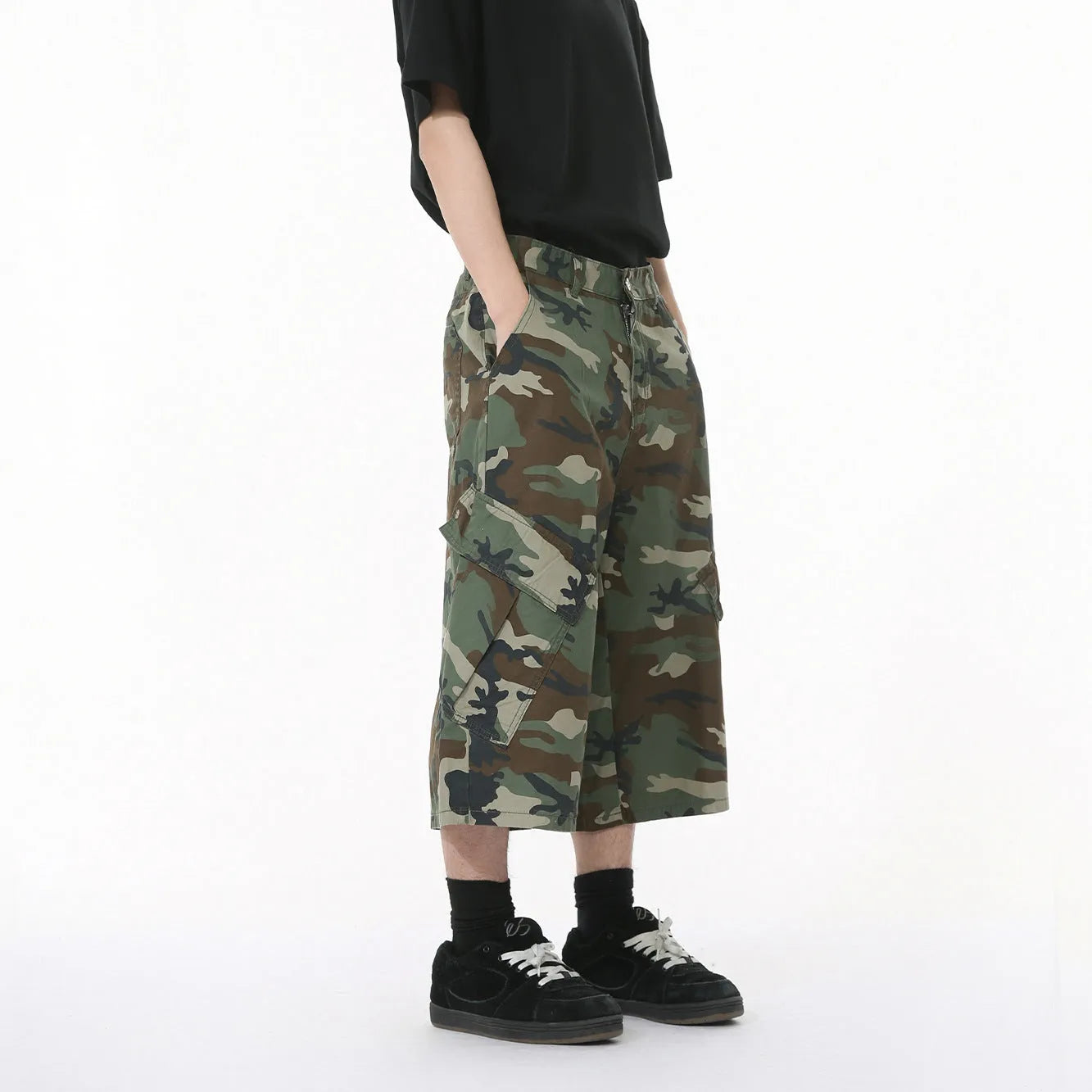 Men's green camouflage cotton trousers with wide loose legs, large side pockets, and cropped length