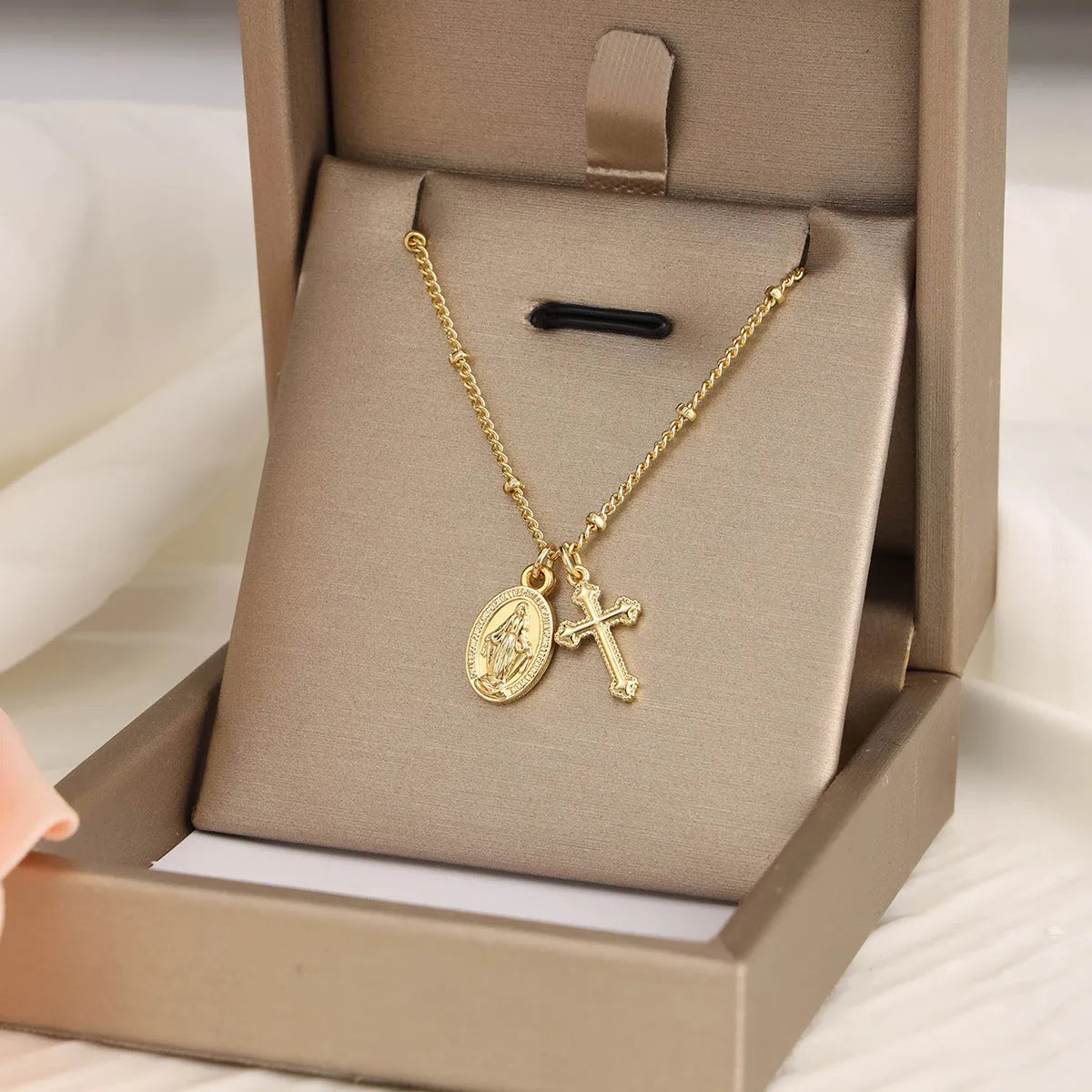 Gold-coloured geometric cross pendant necklace with a Virgin Mary ornament, on a chain.