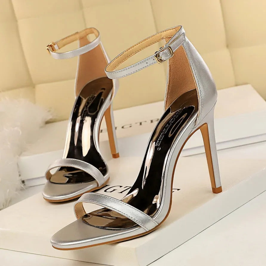 Ankle-strap high heel shoe with open toe and buckle, shown in a solid colour.