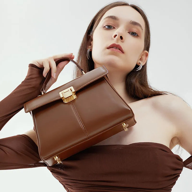 Black leather women's shoulder bag with vachette clasp showing horizontal square shape and adjustable strap