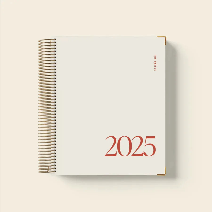 Cherry red spiral coil-bound daily schedule notebook lying open on a table.