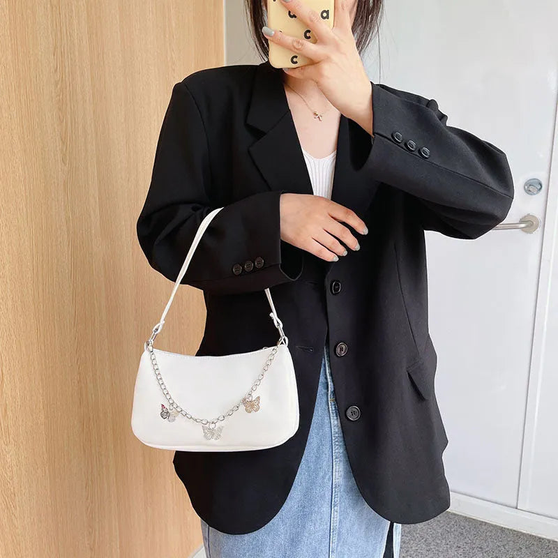 Women's butterfly chain underarm bag in black colour showing crossbody strap and three-dimensional pocket