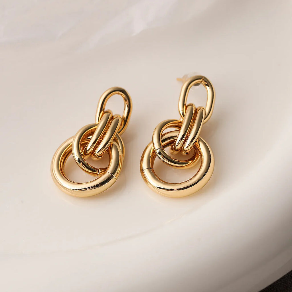 Geometric gold-colour drop earrings with irregular details and high-profile construction