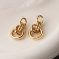 Geometric gold-colour drop earrings with irregular details and high-profile construction