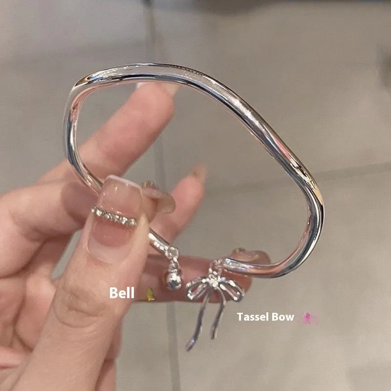 Silver adjustable women's bracelet with a bow bell charm on a zinc alloy bangle.