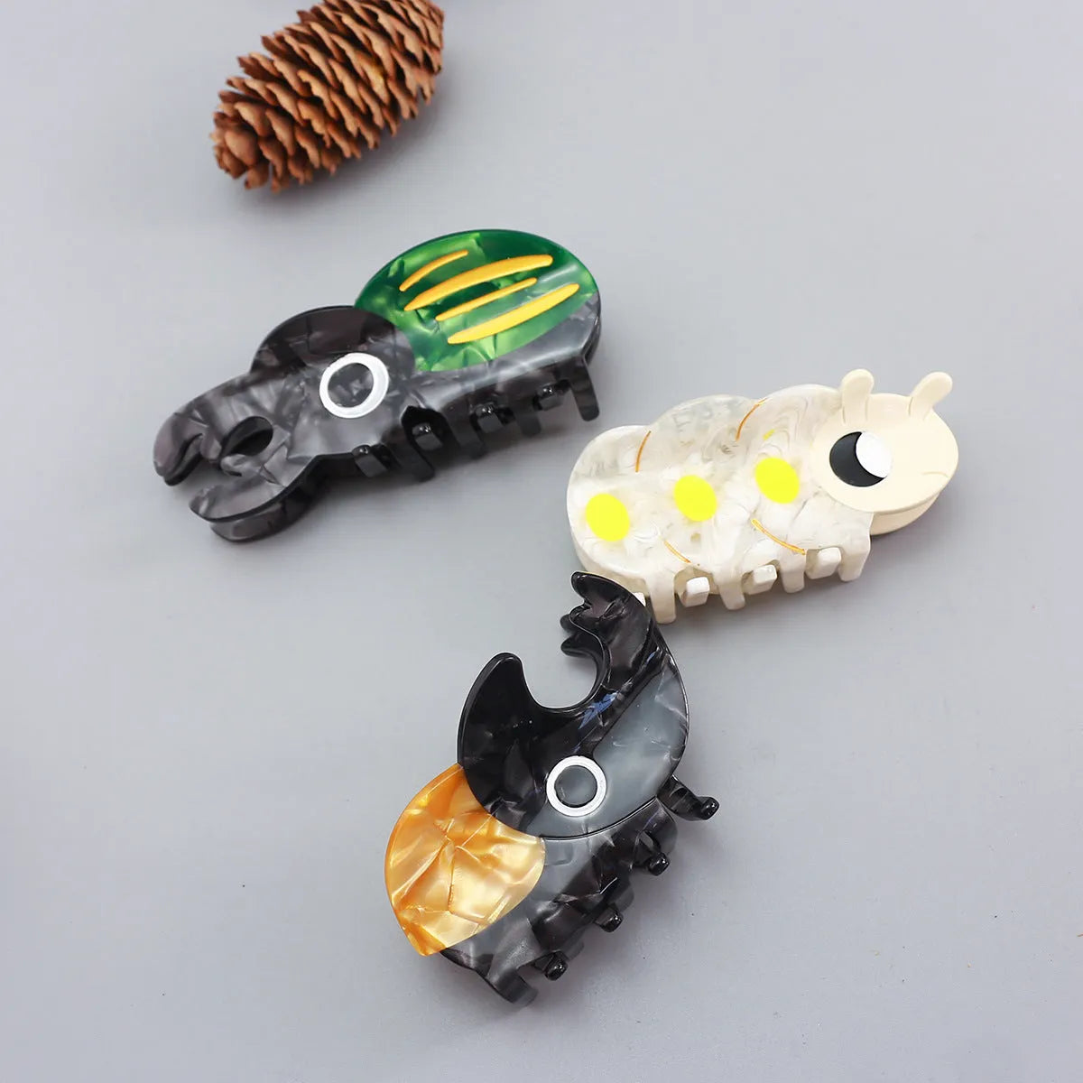 Handmade green and orange beetle grip hair accessory with white cartoon caterpillar design