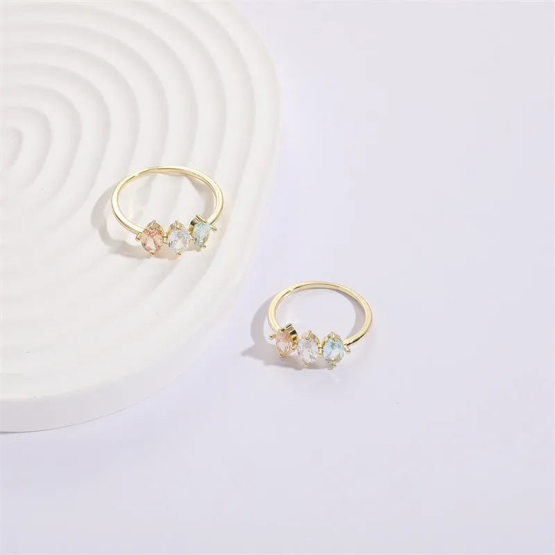 Geometric triangle birthstone ring with tricolour zircon and horse eye motif in gold plating.