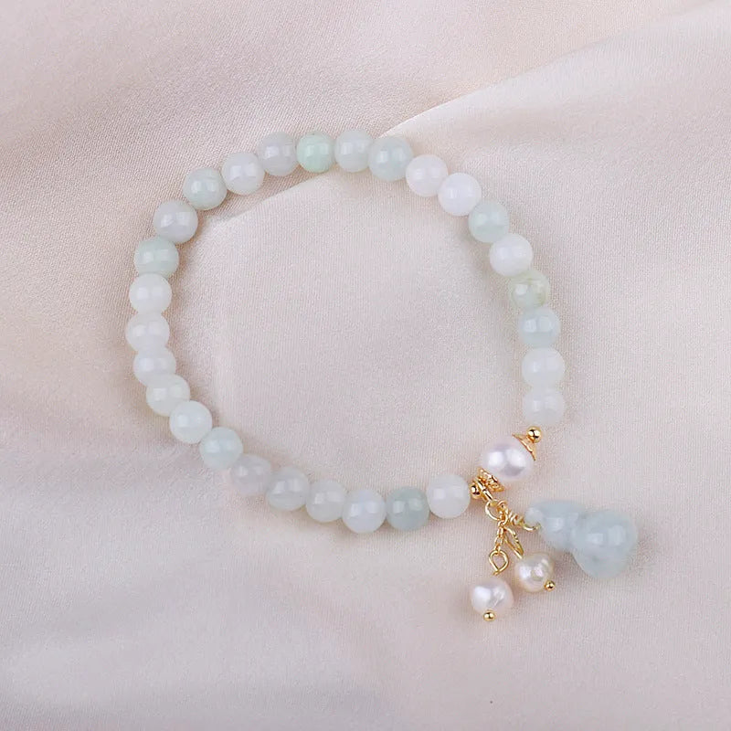 Close-up of a women's jade bracelet with a gourd motif, emerald jade insets, and pearl accents.