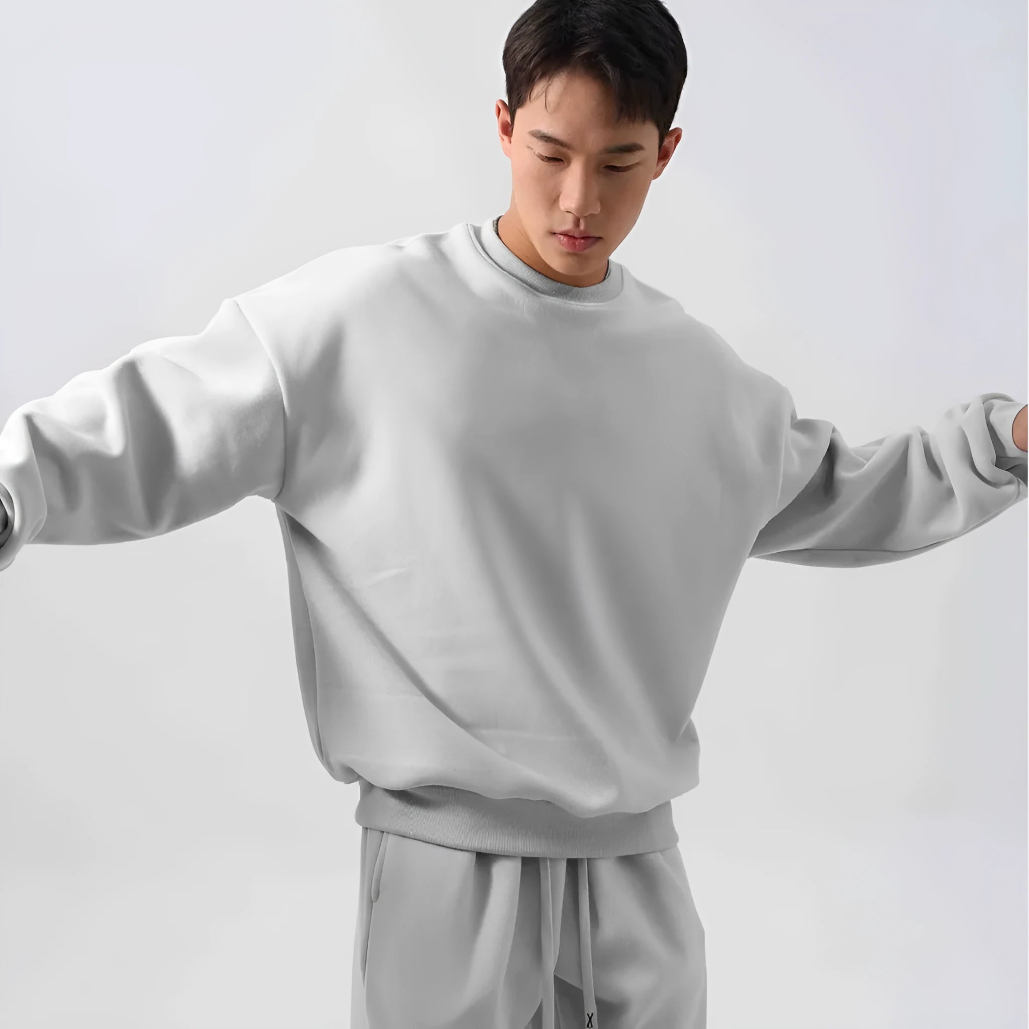 Man wearing a grey polar fleece crew neck coat and matching padded trousers from a casual winter sport suit set.