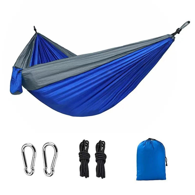 Blue parachute nylon camping hammock hung between two trees showing its full 270 cm length.