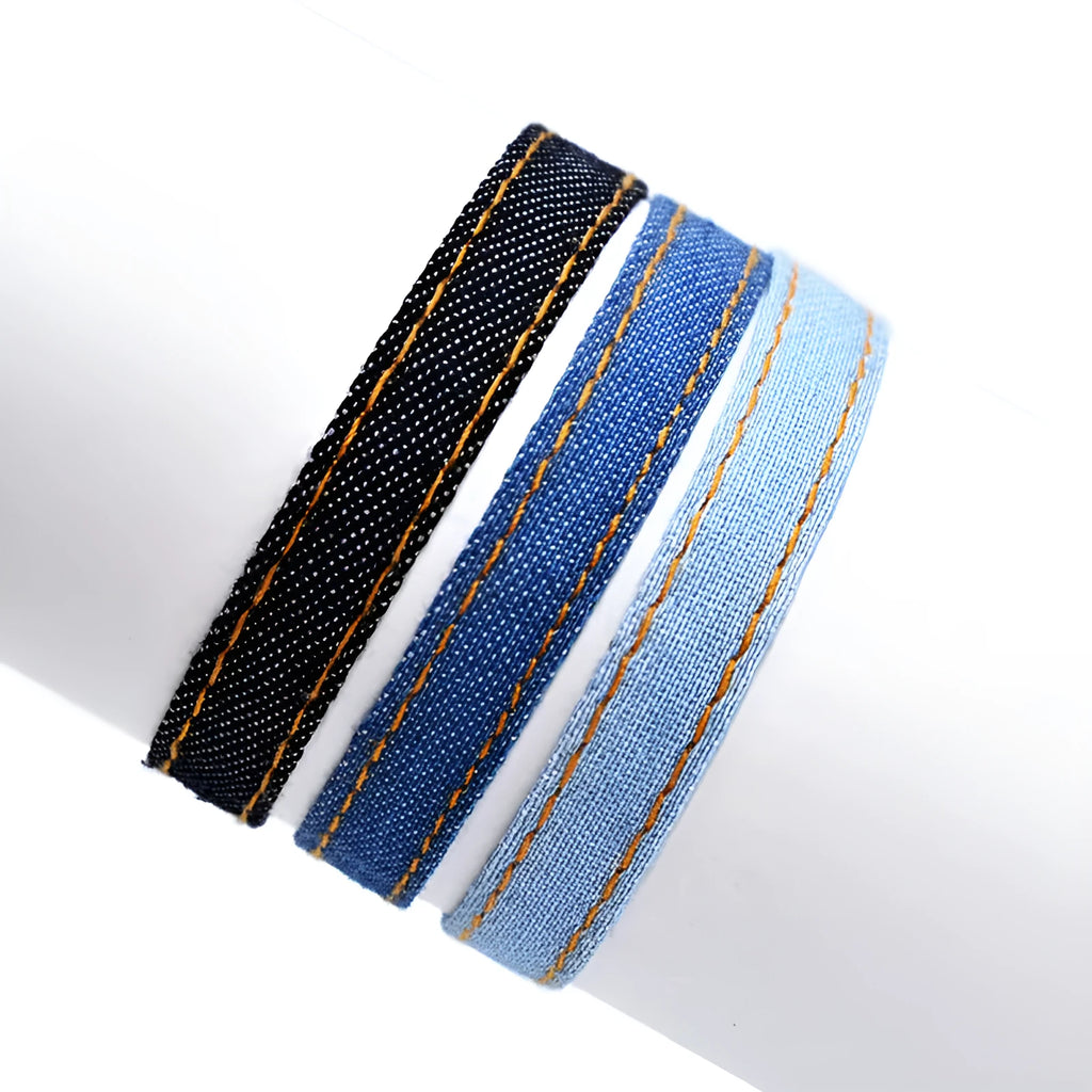 Denim fabric bracelet carrying strap showing mixed material construction and traditional closure mechanism
