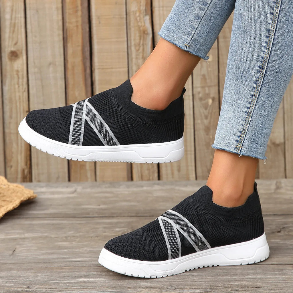Black women's Flyknit mesh flat shoes with a tassel detail on the low-top upper and a flat rubber sole.