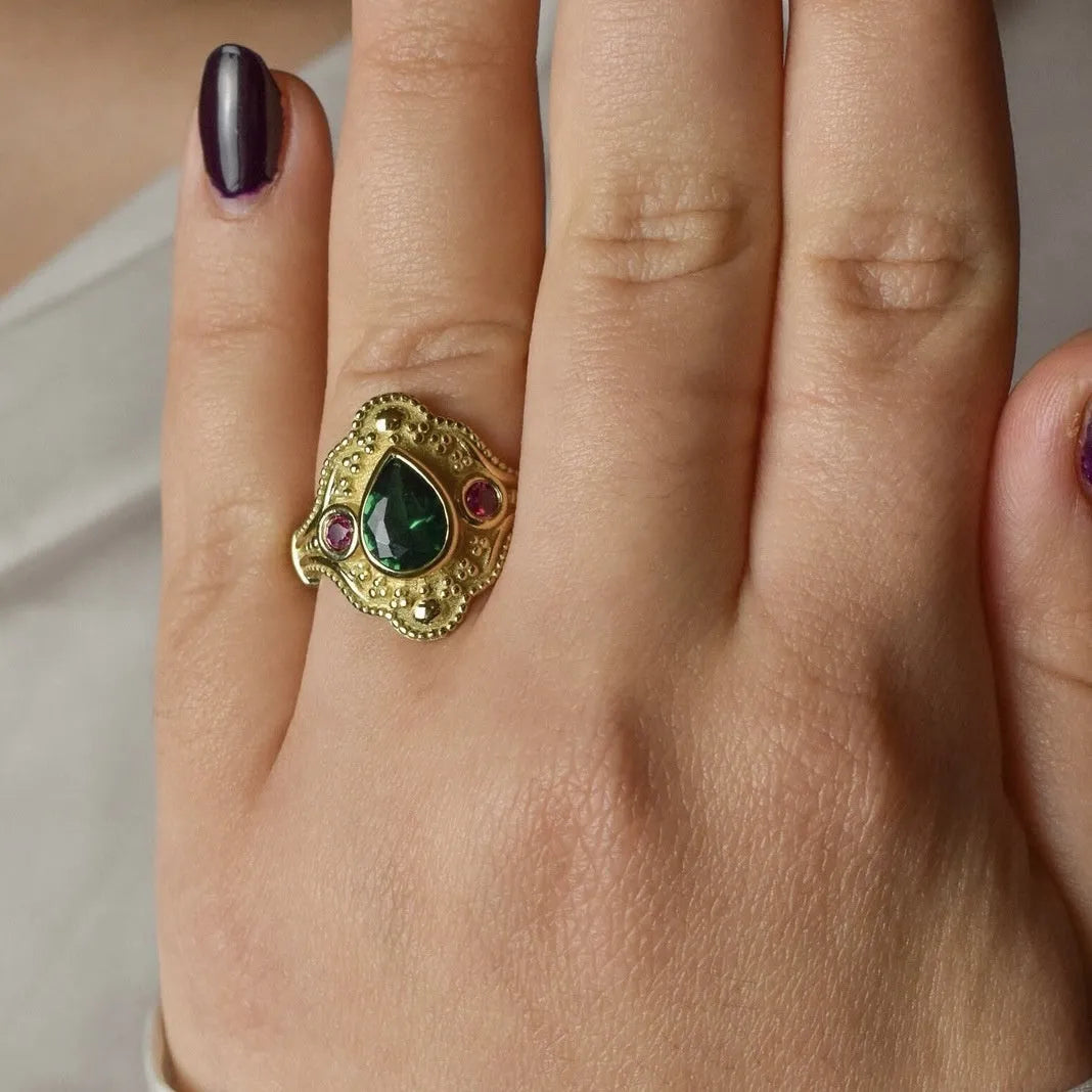 Golden geometric women's ring on a plain background, showing its alloy construction and electroplated finish.