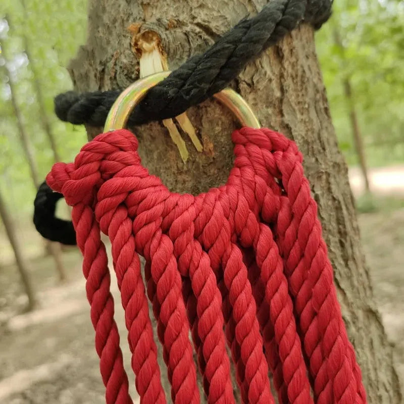 Outdoor nylon rope mesh hammock hung between two trees showing its woven construction and included tying ropes.