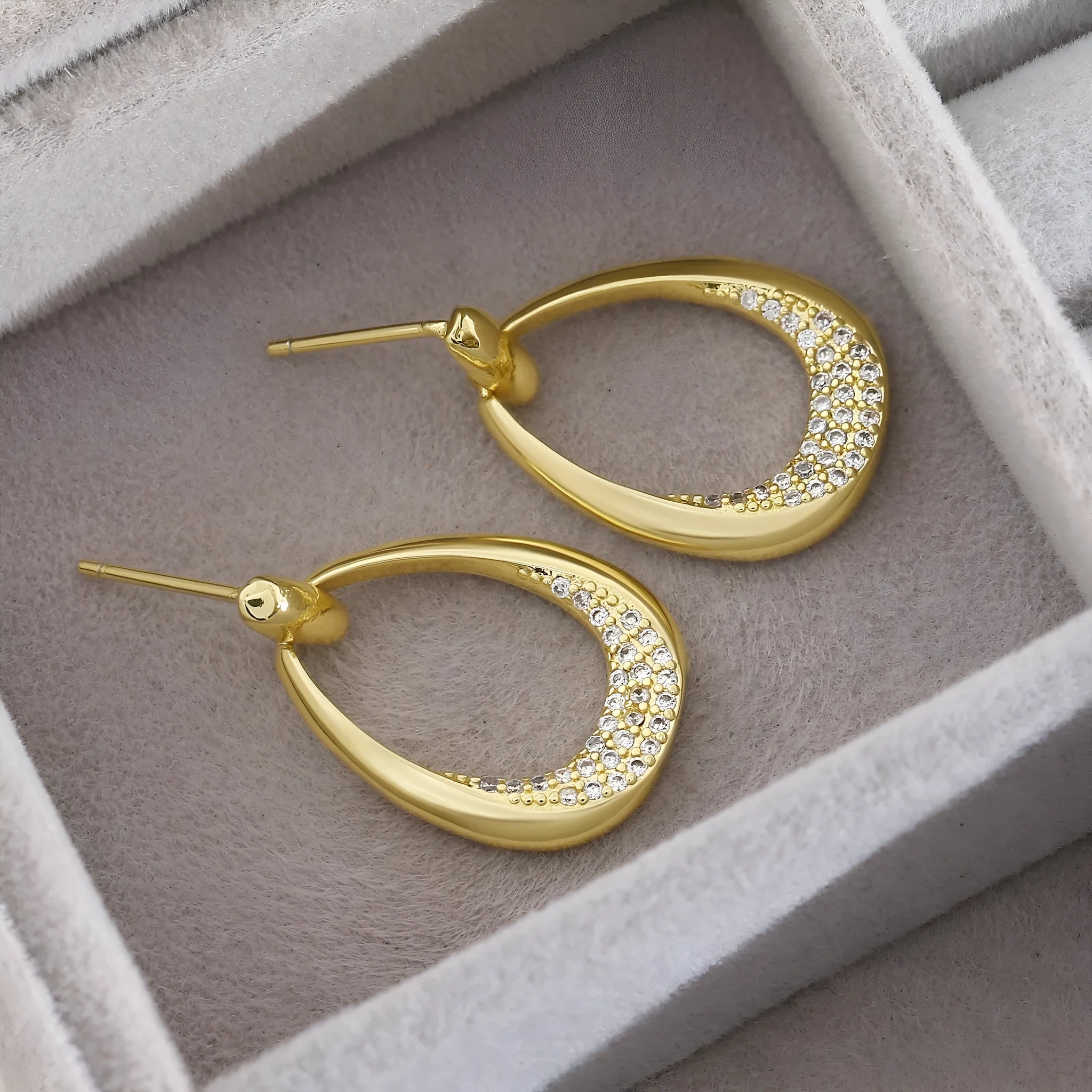 Women's yellow gold geometric drop-shaped earrings with ring design and zircon accents on a white background.