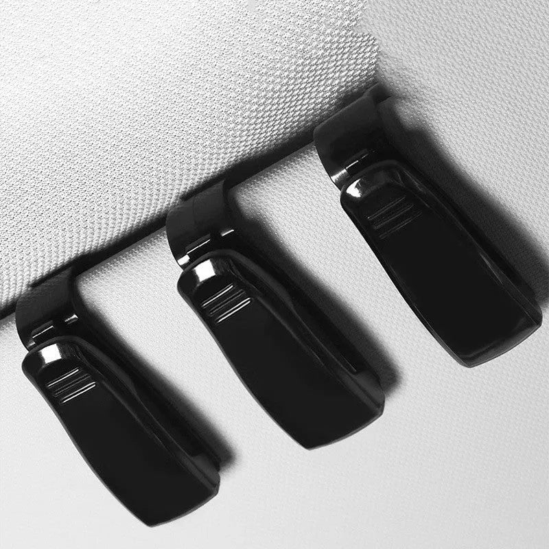 Black plastic multifunctional clip for car sun visor to hold sunglasses, tickets, and ID cards.