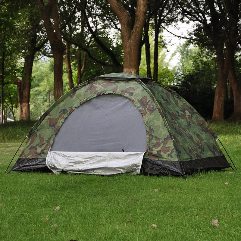 Green camouflage two-person camping tent with fibreglass poles pitched outdoors