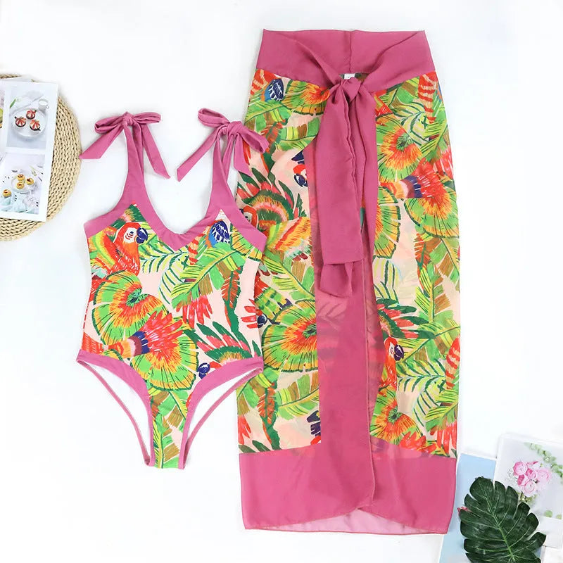 Pink floral retro one-piece swimsuit for women with V-neck and attached skirt on a hanger.
