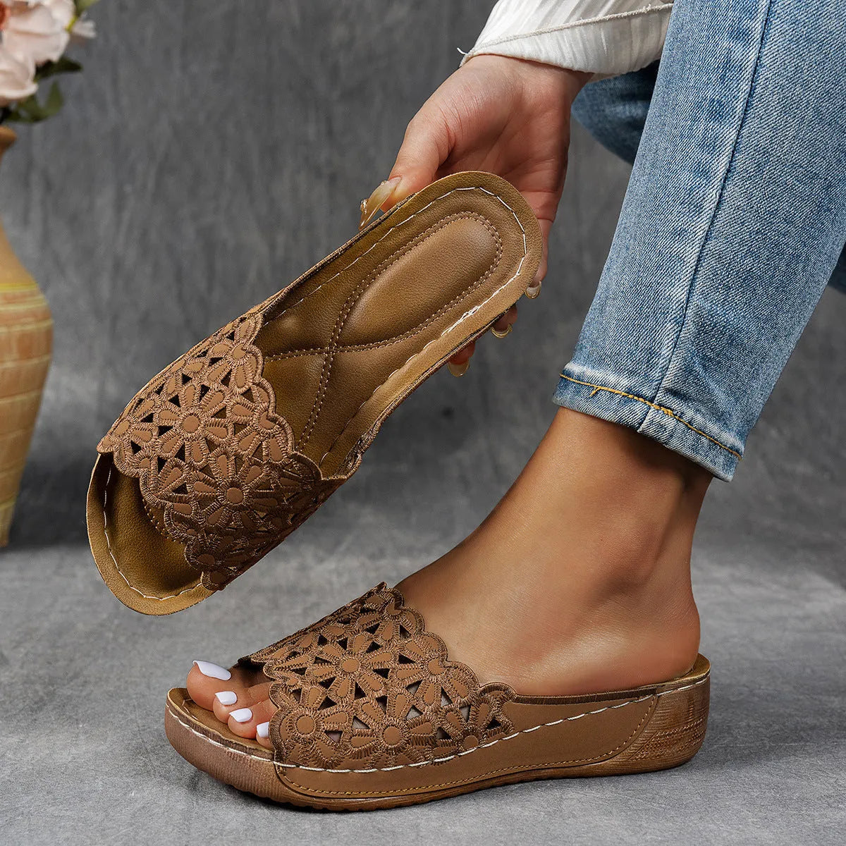 Women's wedge heel beach slippers with flower cutout design on black PVC upper.