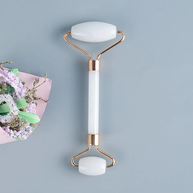 White jade facial roller and gua sha scraping tool set on a storage board.