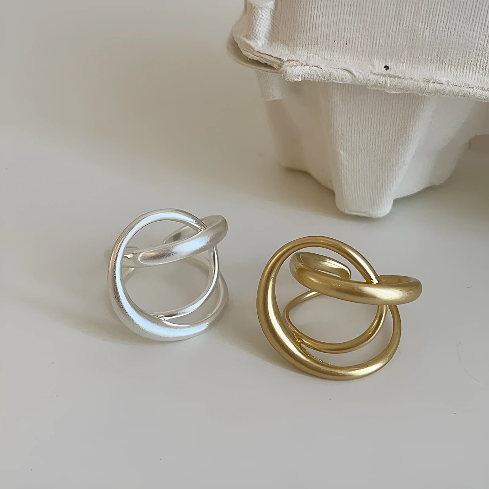 Geometric open ring with three-dimensional interlaced metal and matte electroplated finish in gold or silver colour