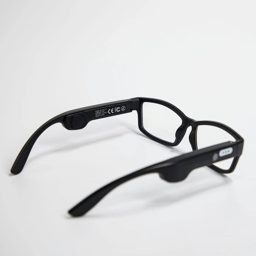 Smart Bluetooth sunglasses with black frame and stereo speakers on a table