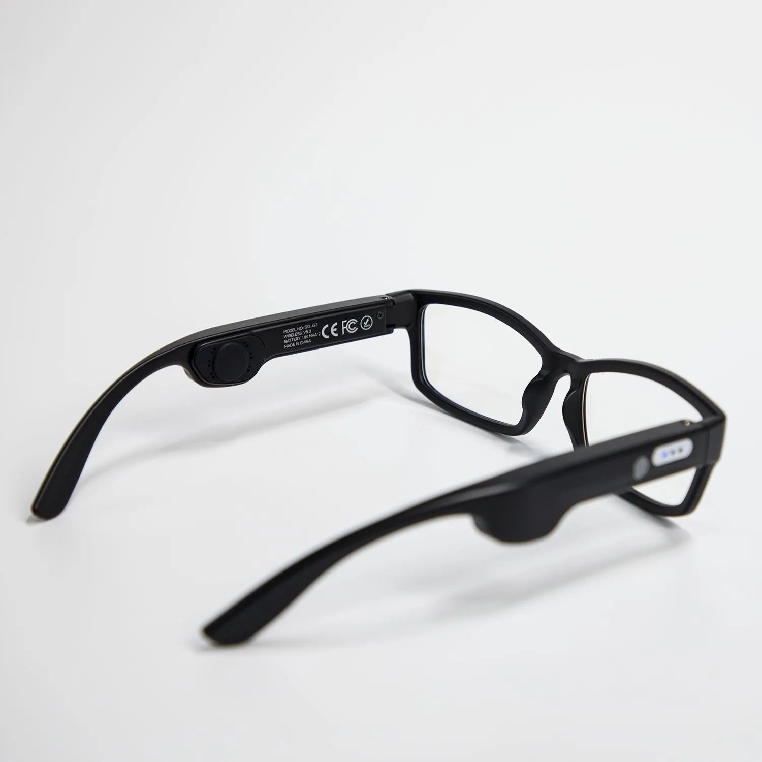 Smart Bluetooth sunglasses with black frame and stereo speakers on a table