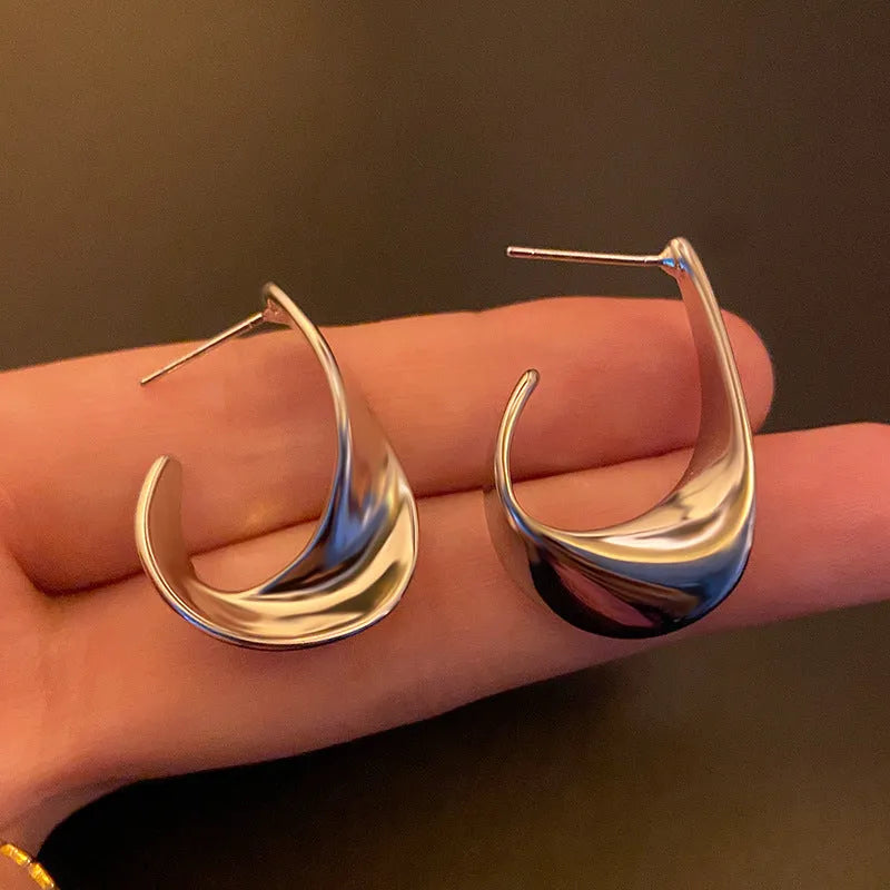Twisted geometric metal earrings with electroplated gold or silver finish and round shape