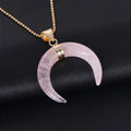 A moon-shaped pendant necklace with a pink natural stone on a copper-coloured chain against a white background.