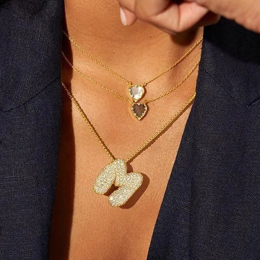 Brass zircon balloon English letter necklace in gold finish, copper base with inlaid zircon stones, on a woman's collarbone
