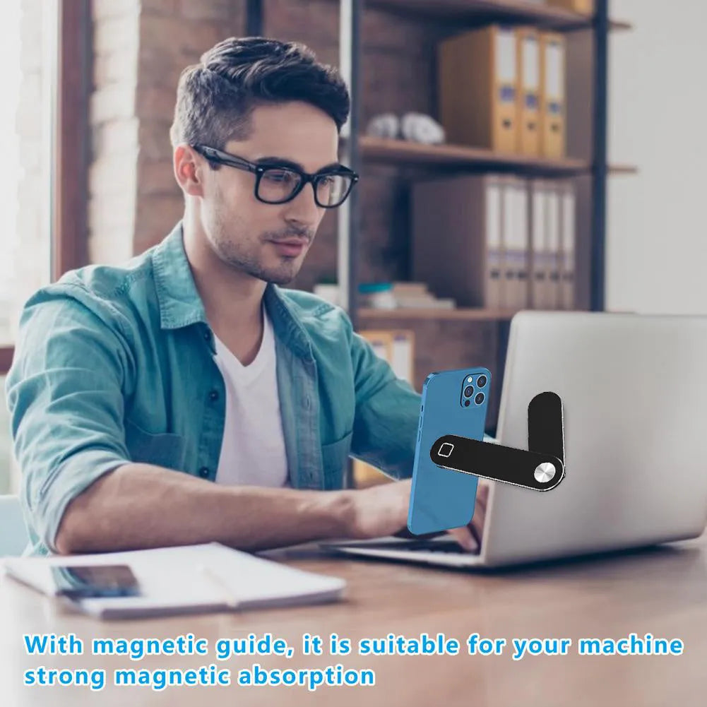 Black magnetic phone holder clipped to the side of a silver laptop, showing a smartphone attached.